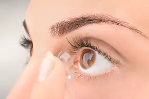 Close-up view of a woman putting a contact lens in her eye.