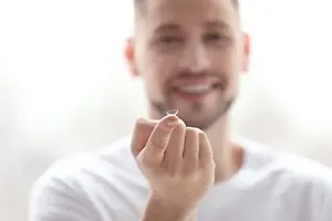 A man is holding a contact lens with a smiling face