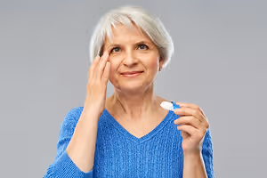 Elderly woman applying eye drops