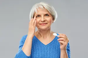 Elderly woman applying eye drops