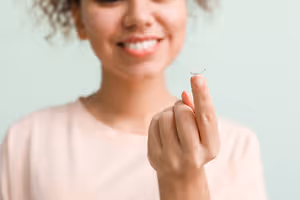 A woman holding a contact lens in her hand