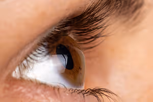 Close-up of a person's eye with eyelashes, cornea, and iris visible