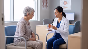 Eye care professional explaining an eye model to an older patient in a clinic