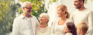 Family standing outside in front of a house with trees in the background