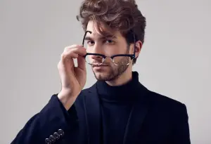 A man with a beard is holding a pair of glasses in his hands.
