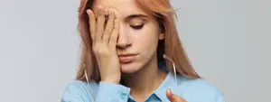 A woman is feeling stressed and holding her head in her hands.