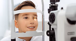 Boy at an eye doctor's office getting his eyes examined with an ophthalmoscope