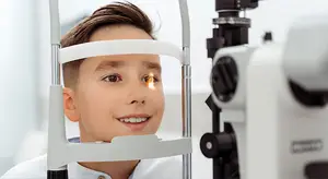 Boy at an eye doctor's office getting his eyes examined with an ophthalmoscope