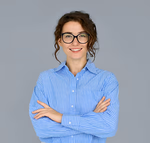 A woman wearing a blue striped shirt with glasses on is smiling and posing for the camera