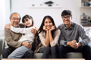 Three adults and a young girl smile and pose for a photo on a couch.