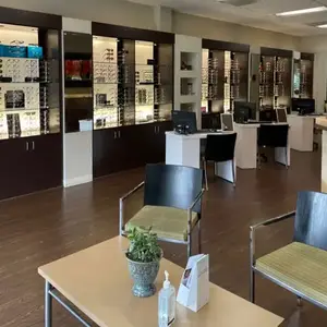 Inside an optical shop with chairs, tables, and displays of glasses and computer monitors