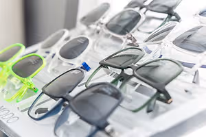 Multiple pairs of sunglasses are displayed in a clear plastic container on a white surface.