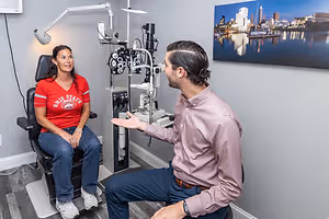 A man and a woman in an eye doctor's office, the woman wearing an Ohio State shirt.