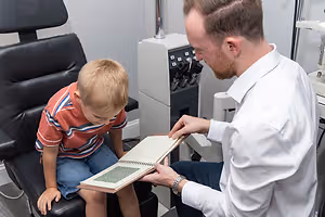 A man with a watch and a beard sitting next to a boy holding a book
