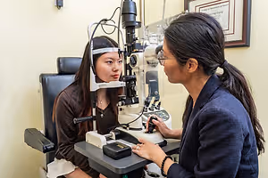 A woman is having her eyes examined by an optometrist in a clinic.