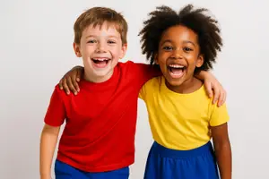 Two children, a boy and a girl, are smiling and standing close to each other with their arms around each other.