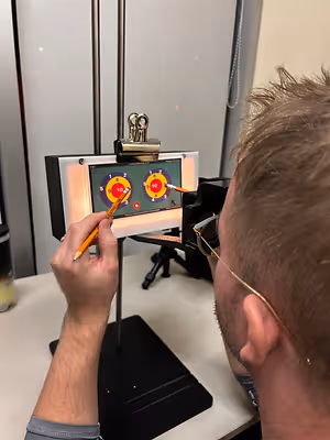 A man wearing glasses is drawing on a digital drawing board with a target on it