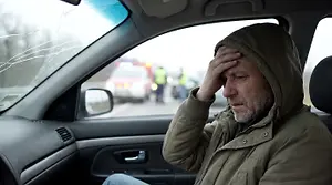 Image of a man sitting in a car, probably after a car accident