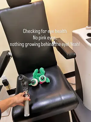 A person examining a stuffed toy's eyes using an ophthalmoscope on a leather chair, accompanied by a caption about eye health.