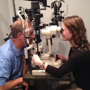 A man having his eye examined by a woman at an optometrist's office