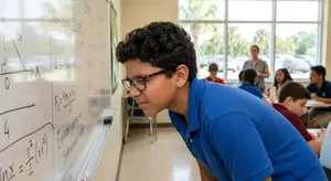 A student is looking at math equations on a whiteboard in a classroom