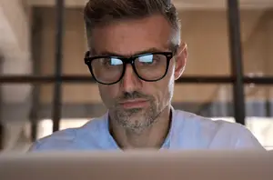 Man with glasses sitting in front of a laptop