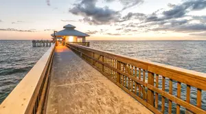 A dock at sunset with a small building at the end.