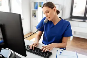 Nurse working at a desk with a phone and computer