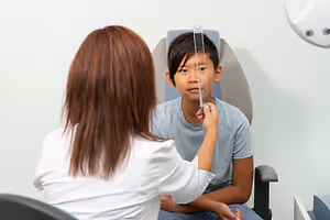 A young boy is having his eyes examined by a doctor in a medical setting.