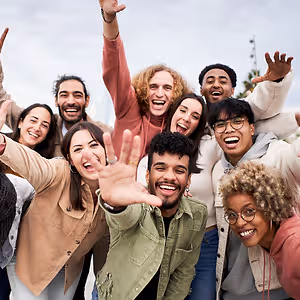 A group of people in different colors are smiling and posing for a photo in an outdoor area.