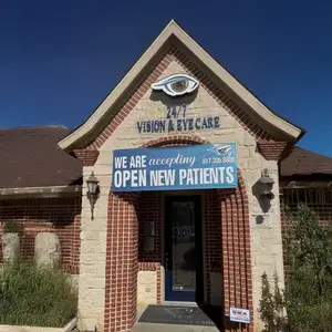 A brick building with a blue banner reading '24/7 Vision & Eye Care' and a glass door is displayed with a blue sky above it.