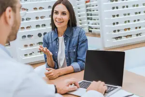 Woman at an optometrist appointment smiling and speaking to the optometrist
