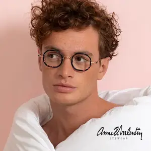 A man with curly hair wearing Anne and Valentin Eyewear glasses and a white shirt