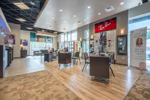 A clean and modern interior of an optical shop with wooden floors and large windows.