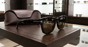 A Tom Ford sunglasses set is displayed on a wooden table in a boutique.
