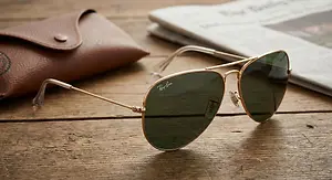 Rayban sunglasses and a brown leather case on a wooden table