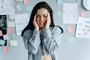 Woman pressing her temples with eyes closed, appearing to have a headache