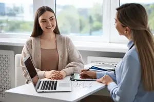 Two women sitting at a table and talking to each other