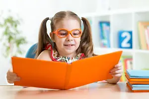 Girl wearing orange glasses reading an orange book