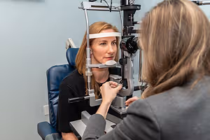 A woman is having an eye examination with another woman at an optometrist's office.