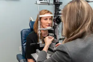 A woman is having an eye examination with another woman at an optometrist's office.