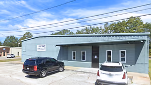 A black SUV and a white car are parked in front of a building with the words 'Tillman Family Eye Care' on a sign.