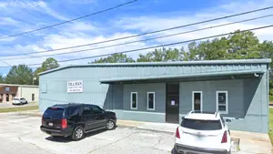 A black SUV and a white car are parked in front of a building with the words 'Tillman Family Eye Care' on a sign.