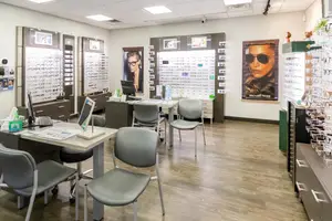 A clean and well-lit optical shop with gray chairs, desks, and a poster of Michael Kors on the wall.