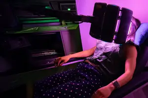 A woman with a light therapy headband is relaxing in a room with a purple light.