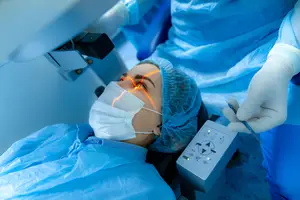 A woman is undergoing eye surgery with a laser in a hospital room