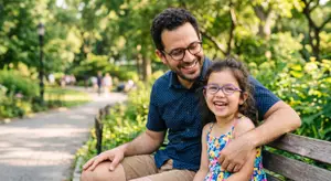 Man and girl sitting on a bench smiling and laughing