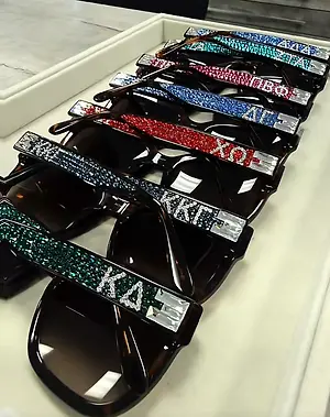 Row of black sunglasses with colorful rhinestone-studded frames displayed on a tray