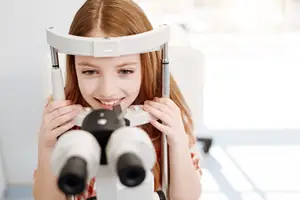 A young girl is getting her eyes checked with an ophthalmoscope in a medical clinic.