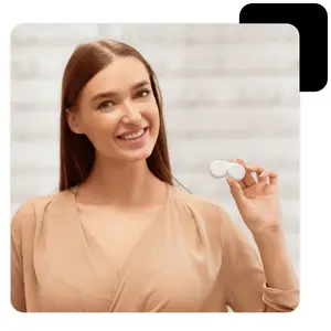 A smiling woman holding contact lenses